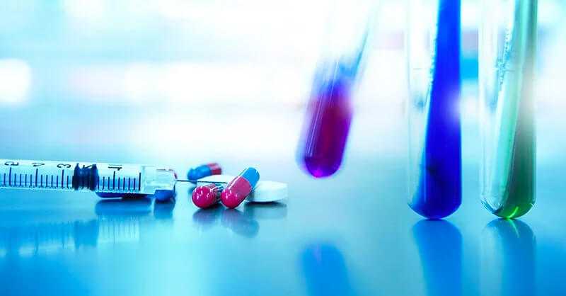 Several laboratory vials, a syringe and pills