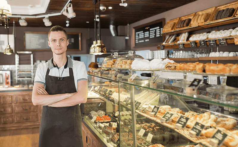 Young man wearing an apron working in a bakery