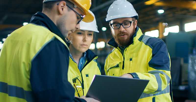 three workers in hard hats talking at a worksite