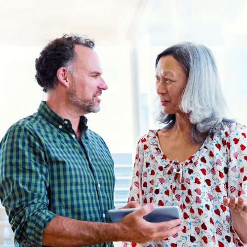 A man and woman at work having a discussion and looking at mobile device