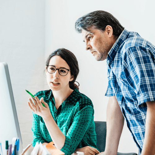 A man and woman looking at a computer screen together at work