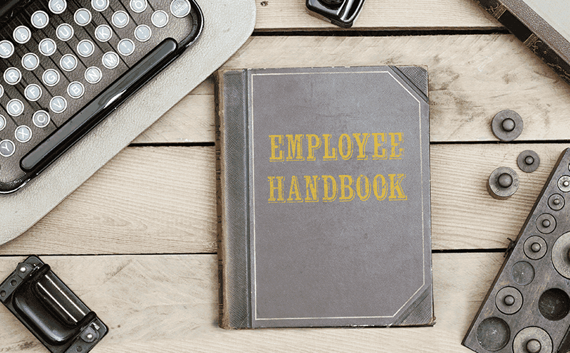 Desk with a book titled Employee Handbook
