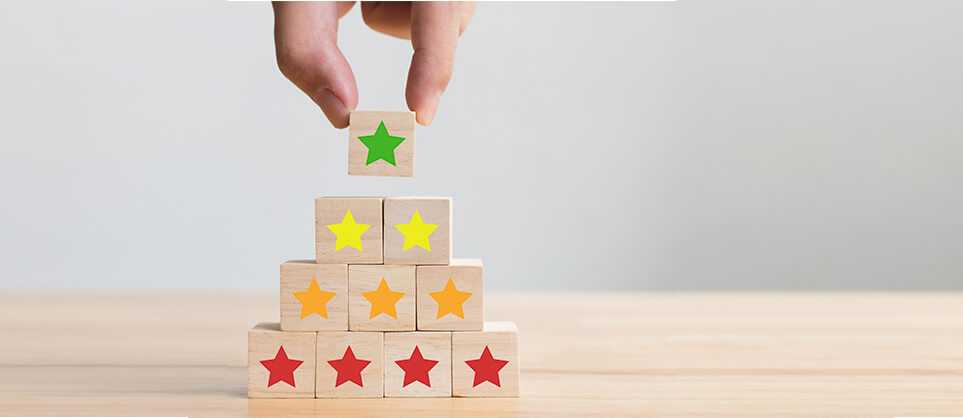 Photo of someone stacking small wooden blocks with red, orange, yellow and green starts on them