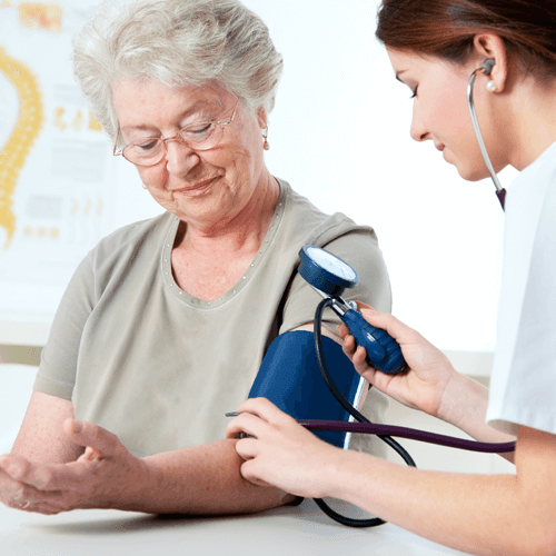 A young nurse is checking the blood pressure of a senior woman