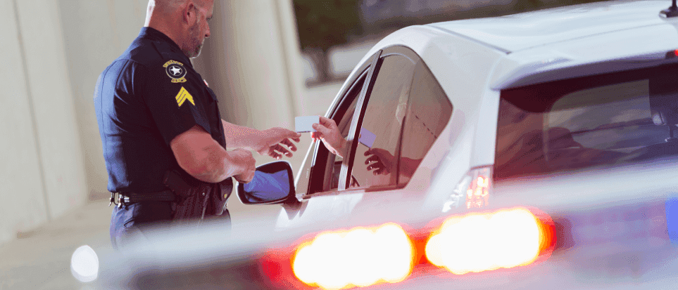 Police officer checking a driver's license by a car