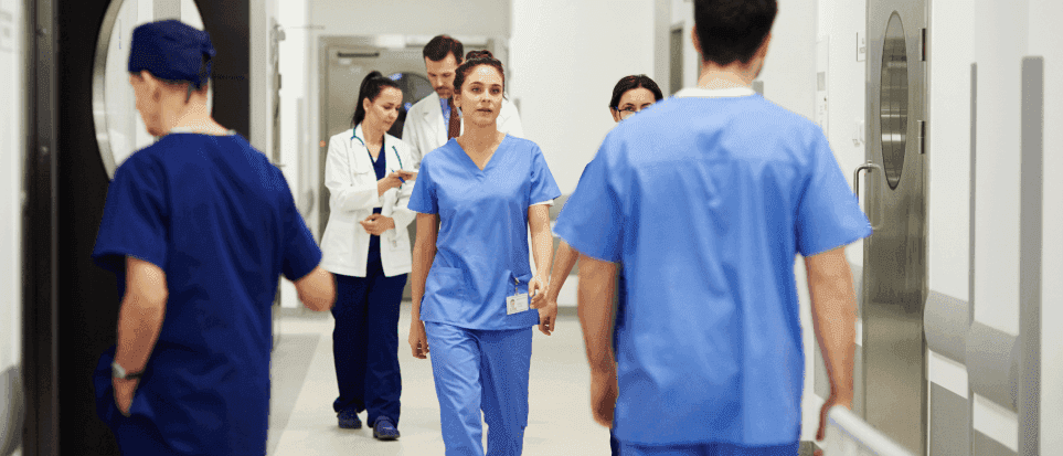 Doctors and nurses walking in a busy hospital corridor.