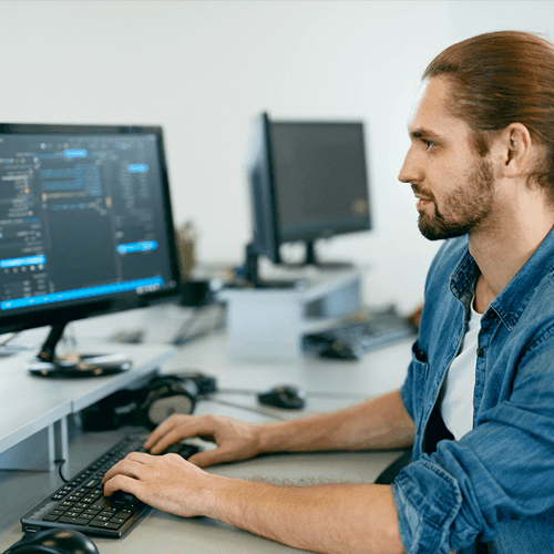 A young man sitting and working at a computer at a tech company