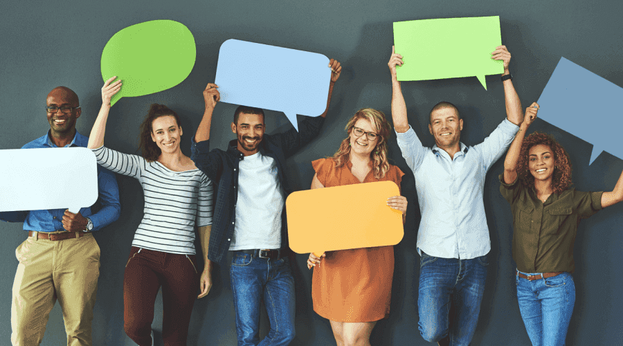 Diverse group of men and women smiling and holding speech bubble cards.