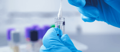 A lab worker wearing gloves dips a cotton swab in a vial to complete saliva drug test for pre-employment.