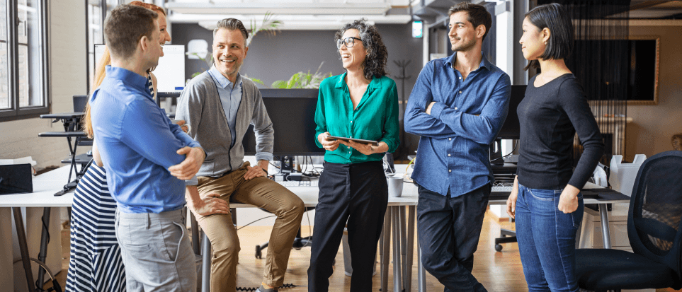 A group of employees of different ages are talking together in an office.