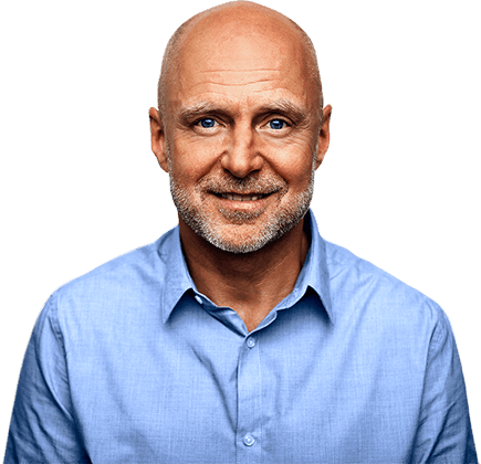 Older man with no hair and short beard wearing blue dress shirt smiling