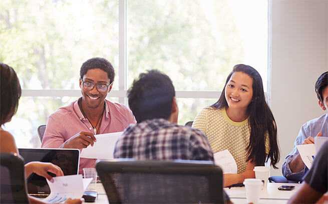 A diverse group of employees sitting around a meeting room table